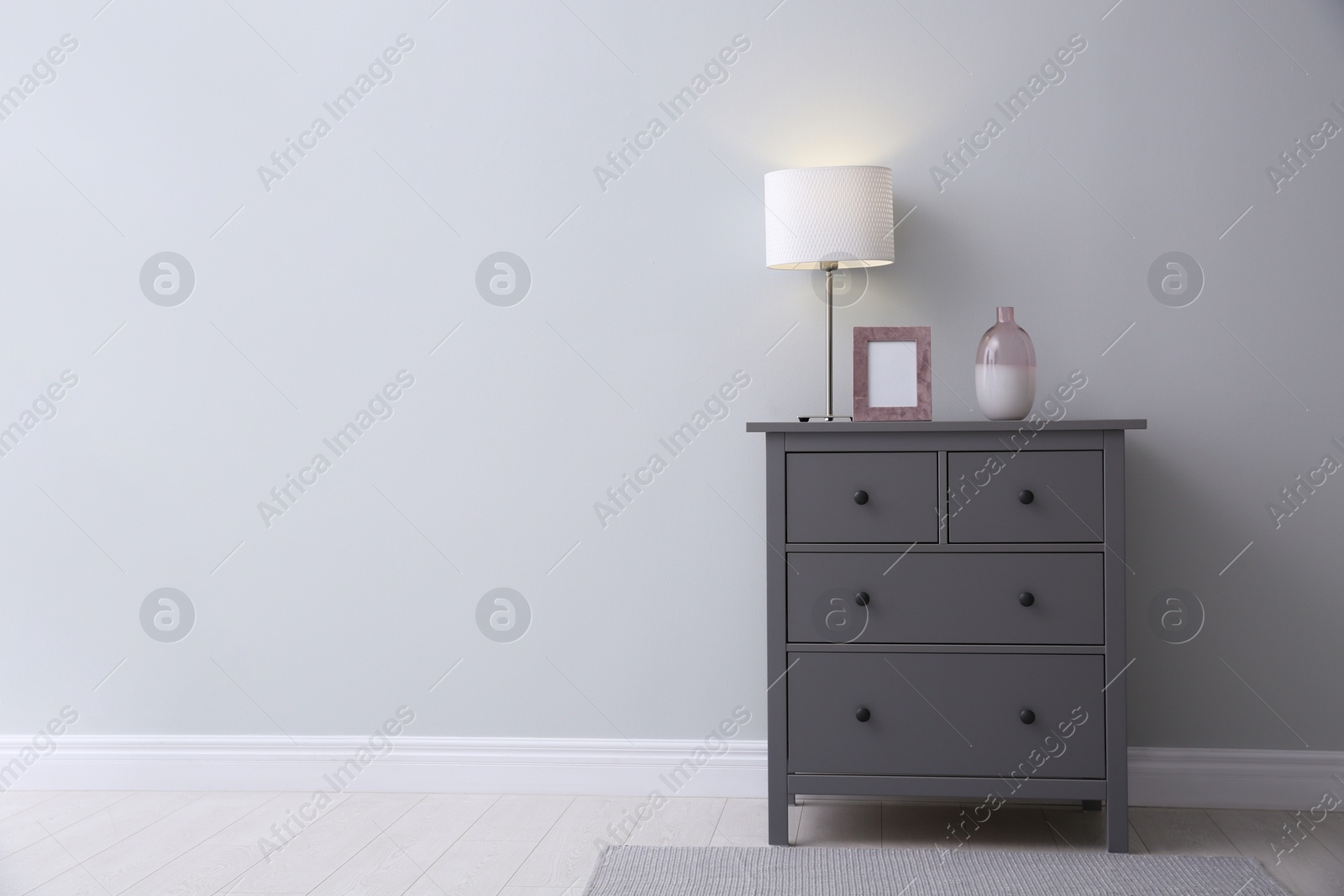 Photo of Modern grey chest of drawers near light wall in room, space for text. Interior design