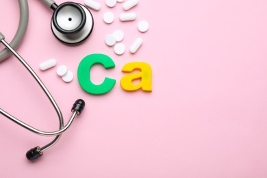 Photo of Stethoscope, pills and calcium symbol made of colorful letters on pink background, flat lay. Space for text