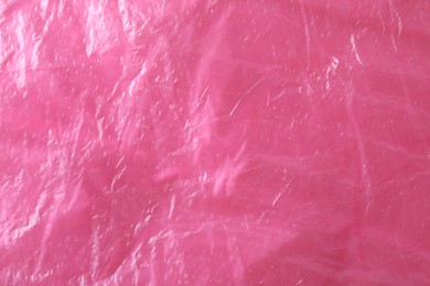 Photo of Texture of bright pink plastic bag as background, closeup