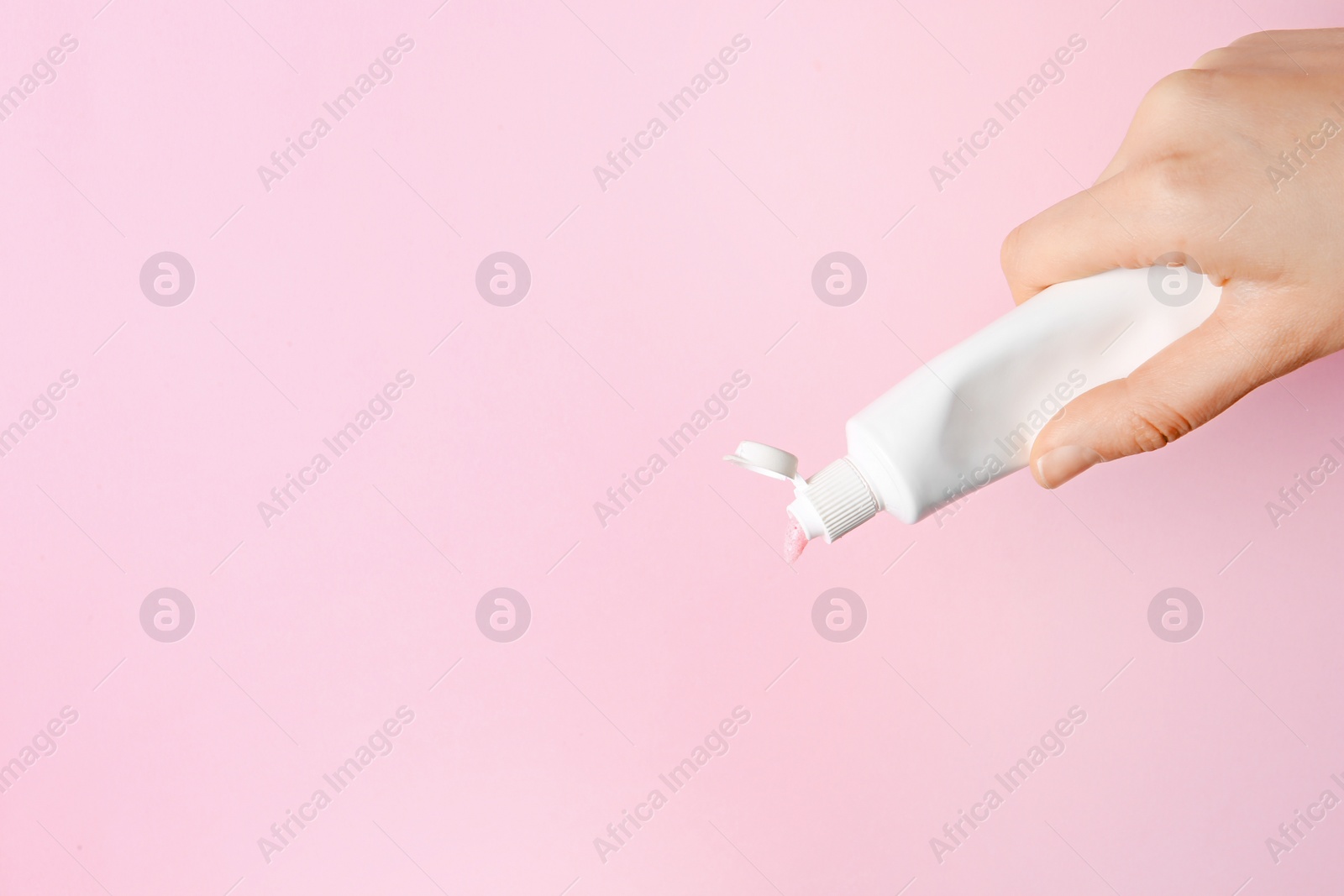 Photo of Woman holding tube of toothpaste on color background