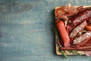 Different types of sausages served on light blue wooden table, top view. Space for text