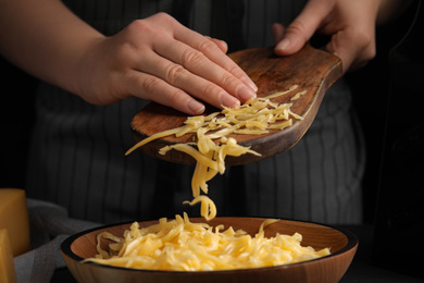 Photo of Woman with grated cheese at table, closeup