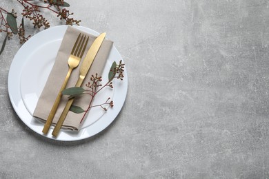 Stylish table setting with cutlery and eucalyptus leaves, top view. Space for text