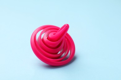 Photo of One pink spinning top on light blue background, closeup