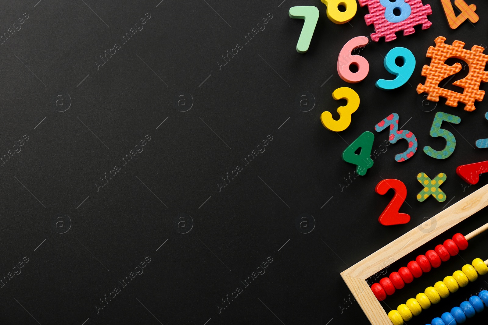 Photo of Many colorful numbers and mathematical symbols near abacus on black background, flat lay. Space for text