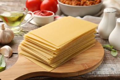 Stack of pasta sheets and other products for cooking lasagna on wooden rustic table, closeup