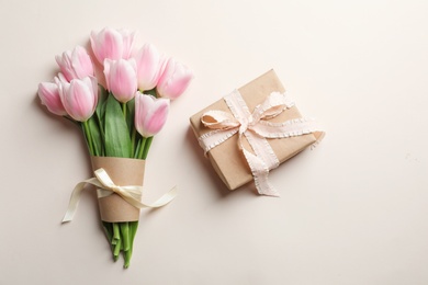 Photo of Beautiful tulips and gift box for Mother's Day on light background, top view