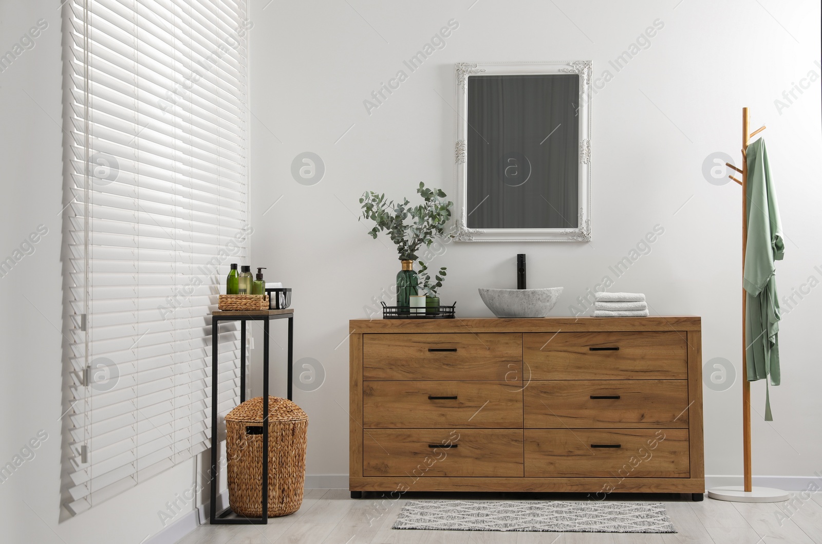 Photo of Modern bathroom interior with stylish mirror, eucalyptus branches, vessel sink and wooden vanity