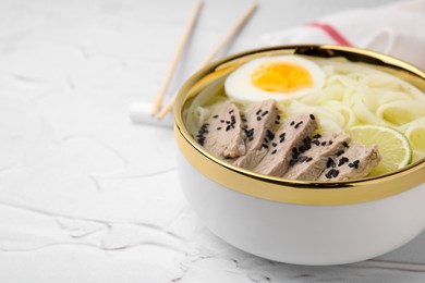 Photo of Bowl of delicious rice noodle soup with meat and egg on white textured table, closeup. Space for text