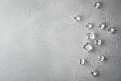 Photo of Crystal clear ice cubes with water drops on light grey table, flat lay. Space for text