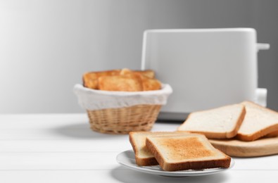 Photo of Slices of tasty toasted bread on white wooden table, space for text