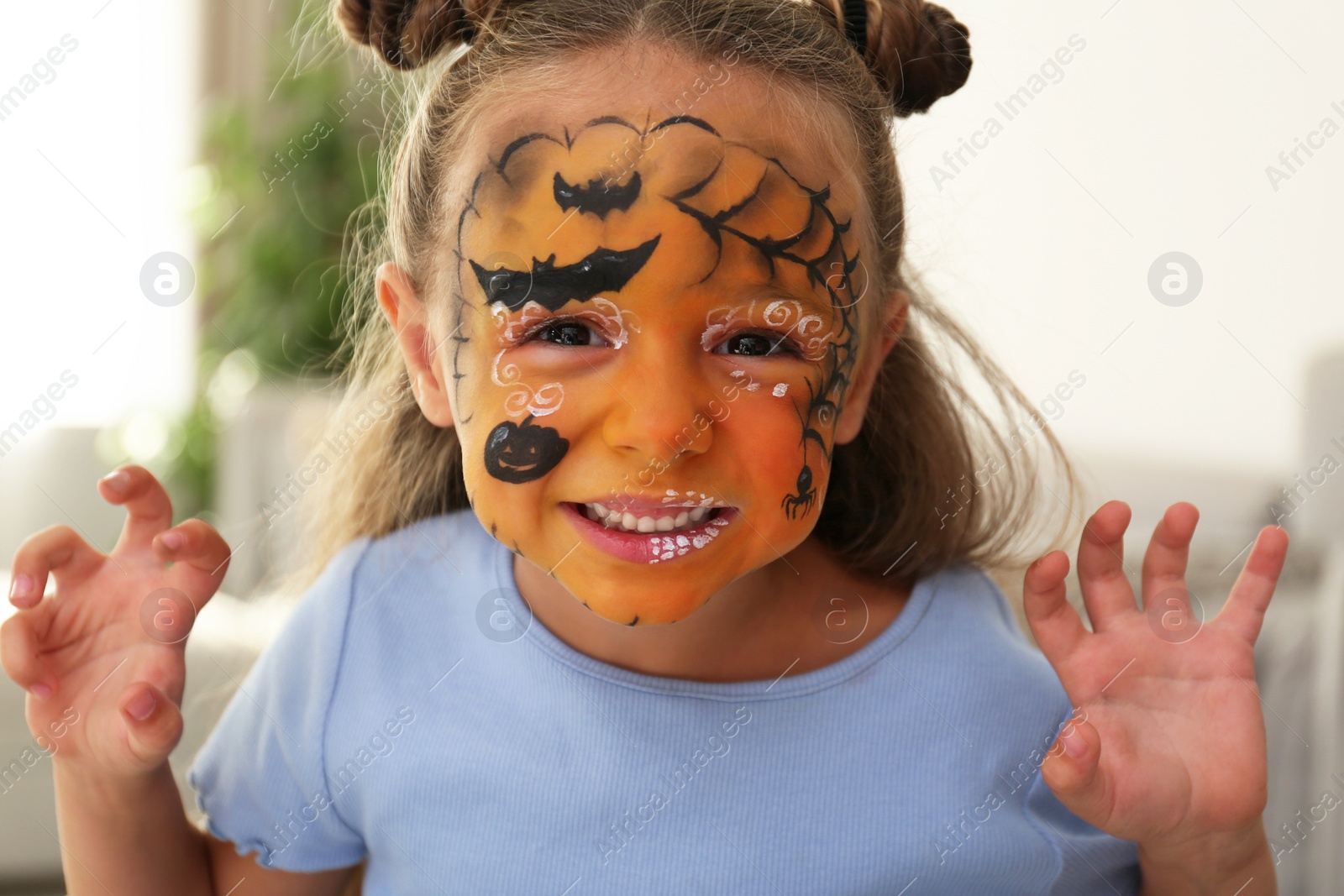 Photo of Cute little girl with face painting indoors