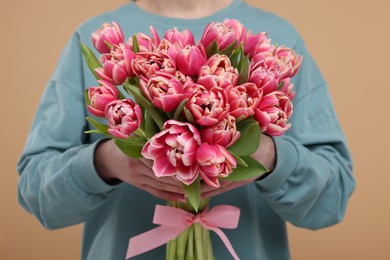 Photo of Woman holding beautiful bouquet on beige background, closeup