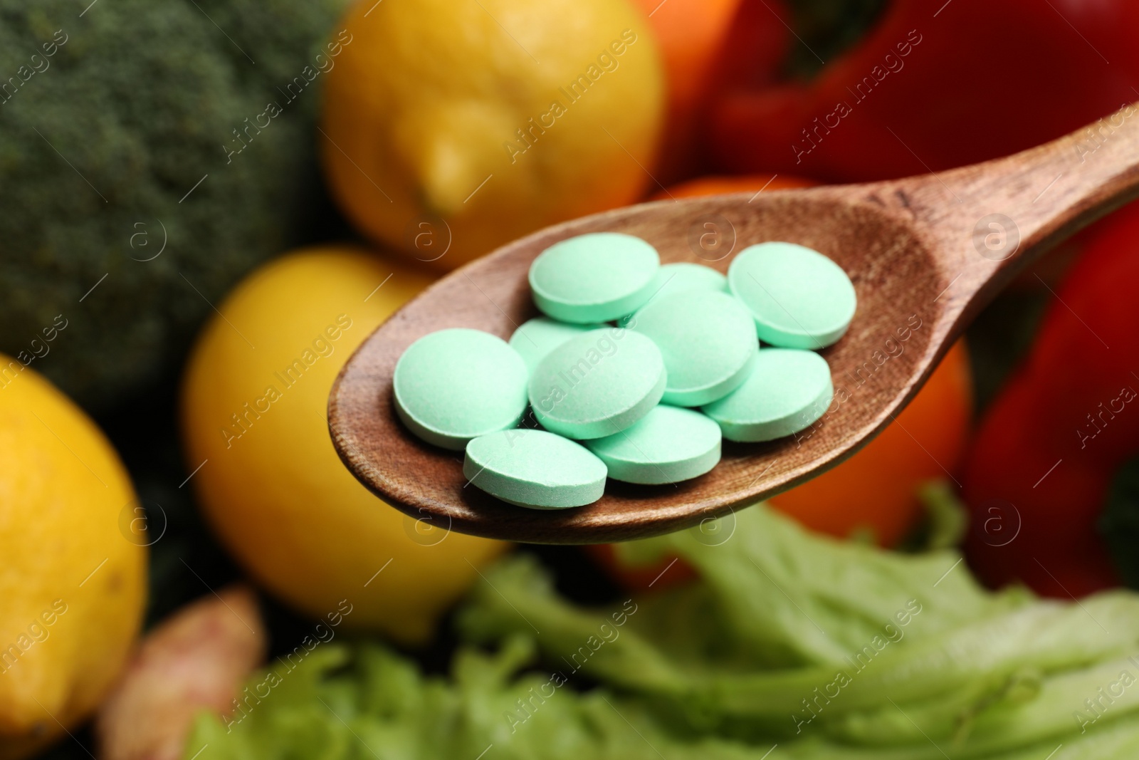 Photo of Dietary supplements. Spoon with pills over food products, closeup