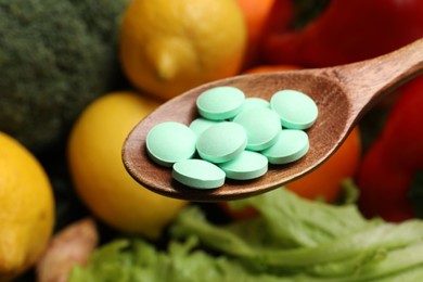 Photo of Dietary supplements. Spoon with pills over food products, closeup