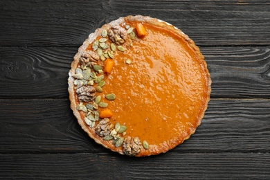 Photo of Delicious fresh homemade pumpkin pie on black wooden table, top view