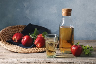 Delicious cider and red apples with green leaves on wooden table