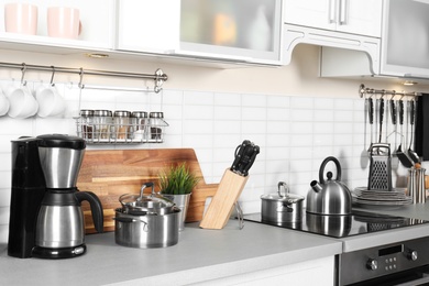 Photo of Different appliances, clean dishes and utensils on kitchen counter