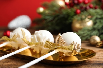 Photo of Delicious Christmas themed cake pops on golden plate, closeup