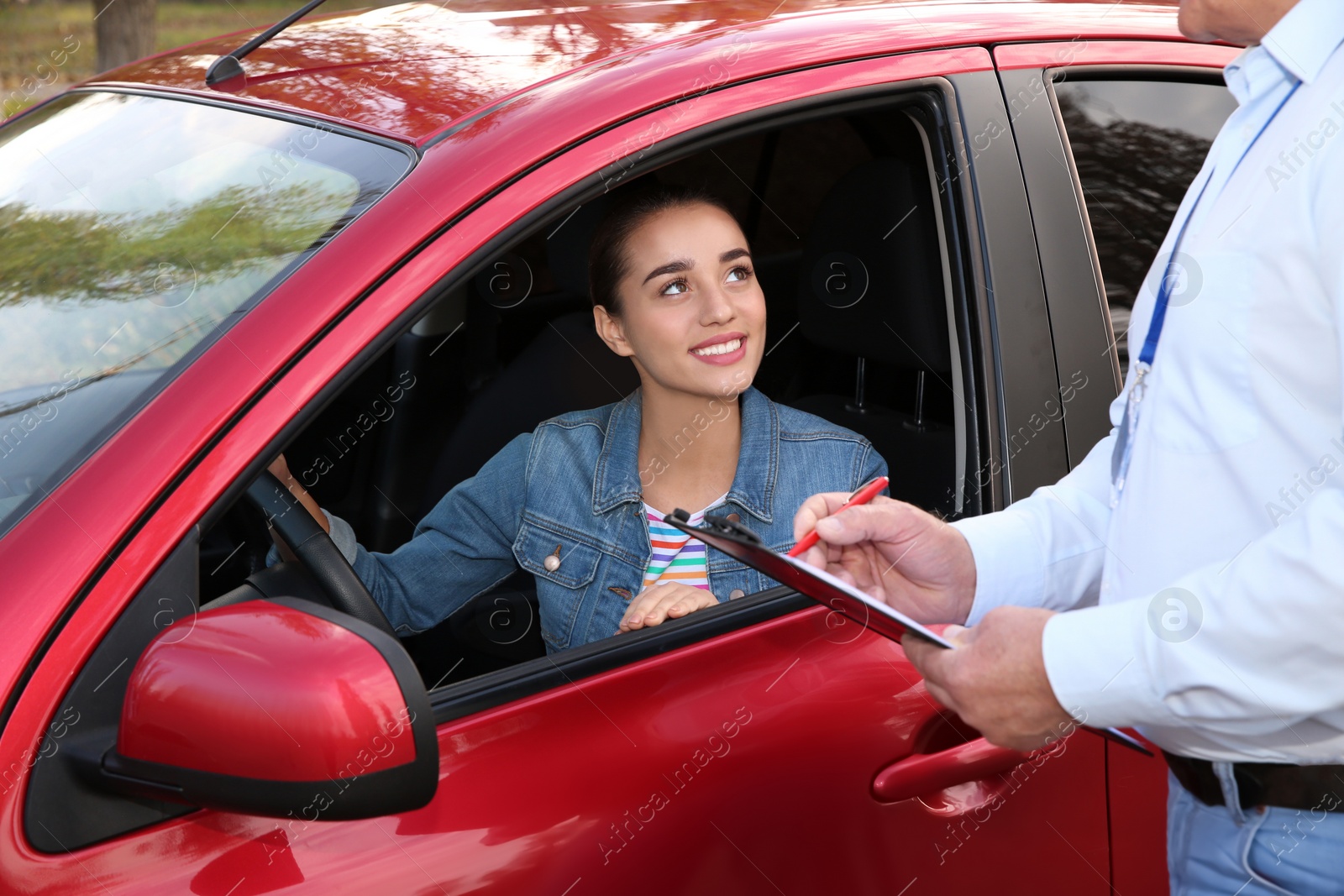 Photo of Instructor near woman in car, outdoors. Passing driving license exam