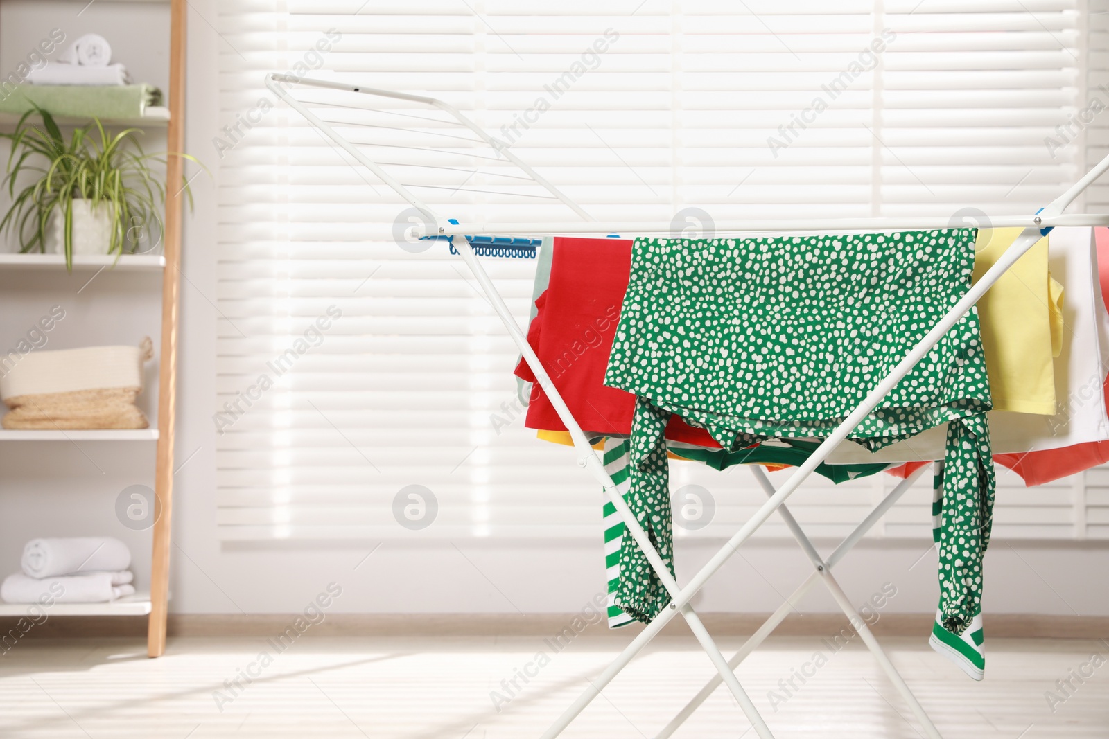 Photo of Different apparel drying on clothes airer in room, space for text