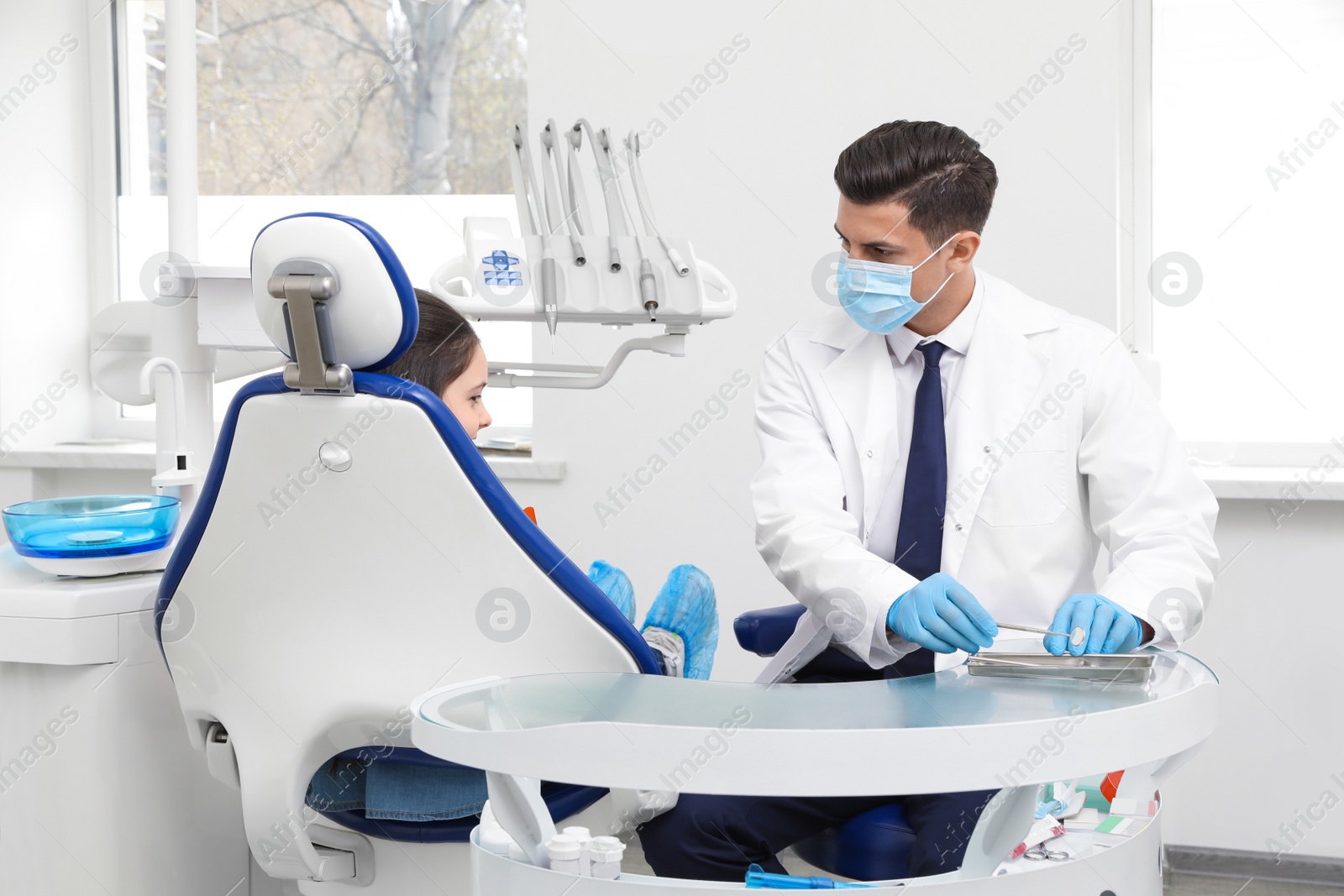 Photo of Professional dentist working with little girl in clinic