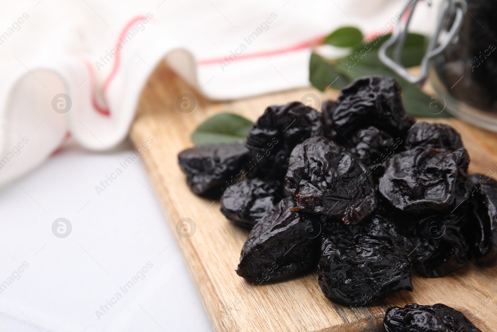 Photo of Tasty dried prunes on light table, closeup view