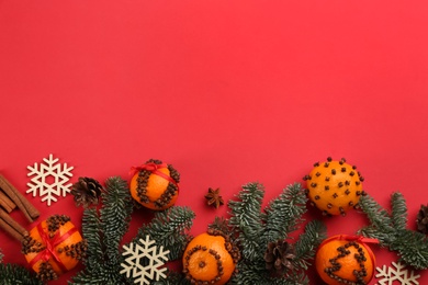 Flat lay composition with pomander balls made of fresh tangerines on red background. Space for text