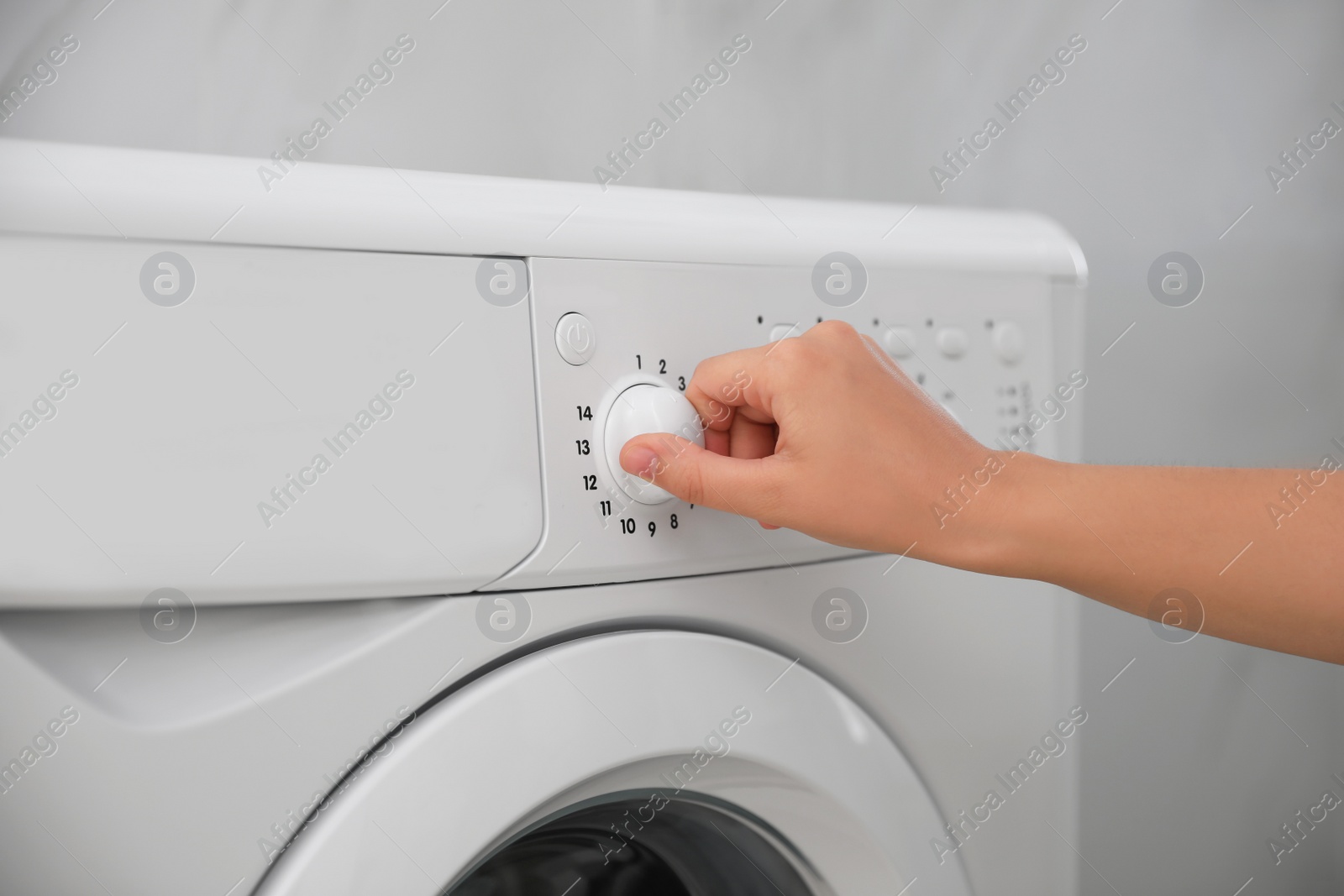 Photo of Woman turning on washing machine in bathroom, closeup. Laundry day