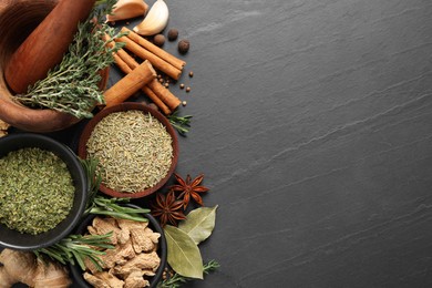 Photo of Flat lay composition with different natural spices and herbs on black table, space for text