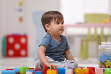 Cute little child playing with toys on floor at home