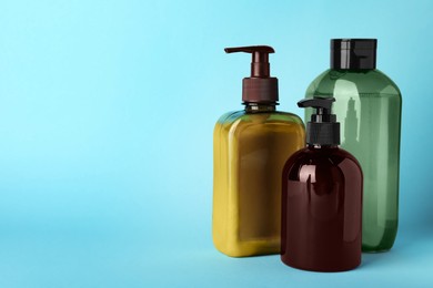 Photo of Bottles of shampoo on light blue background, space for text