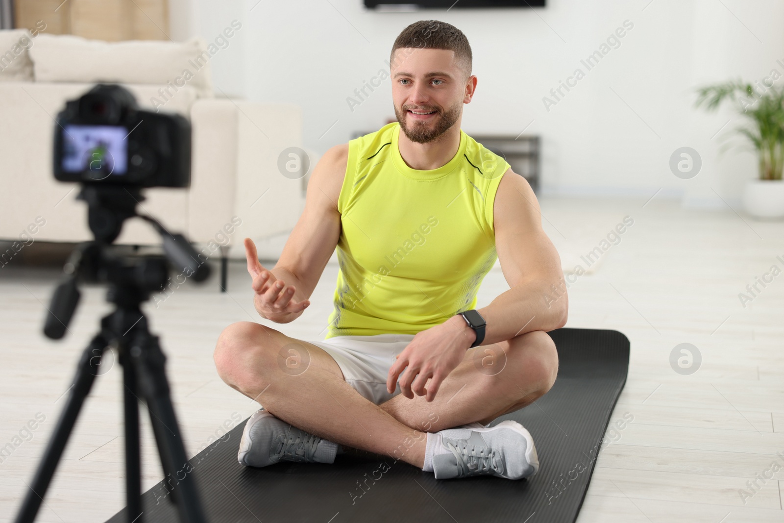 Photo of Trainer recording fitness lesson on camera at home