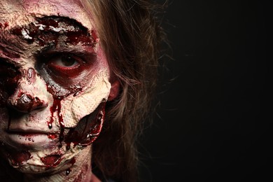 Scary zombie on dark background, closeup with space for text. Halloween monster