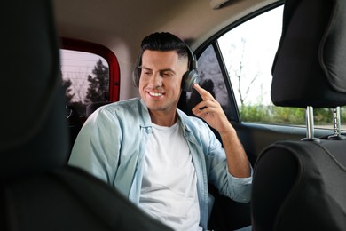 Photo of Man listening to music in modern taxi