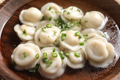 Photo of Bowl of tasty dumplings in broth, closeup