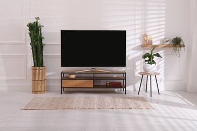 Photo of Modern TV on stand near white wall indoors. Interior design