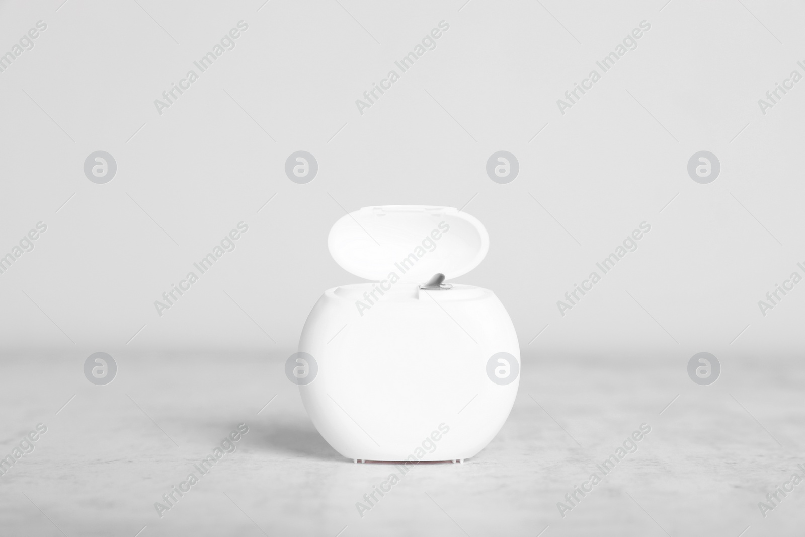 Photo of Container with dental floss on light grey textured table