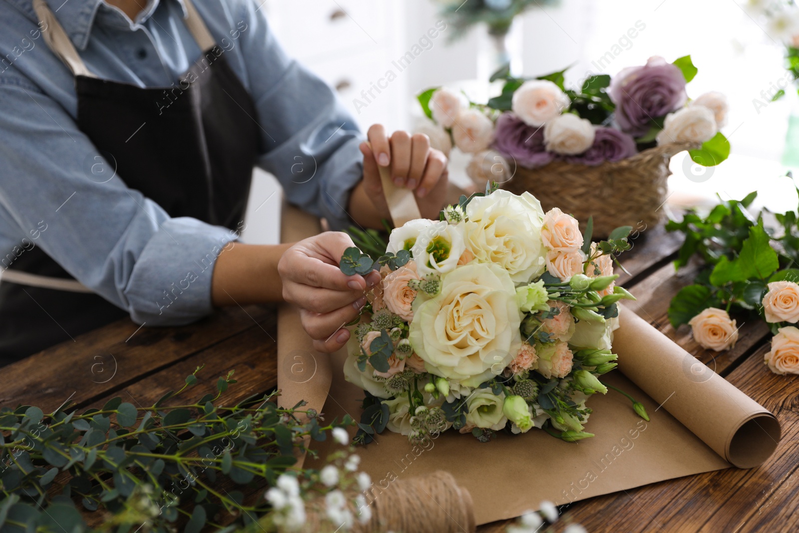 Photo of Florist making beautiful wedding bouquet at wooden table, closeup