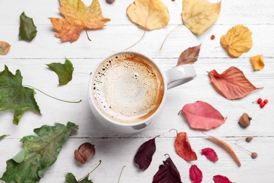 Flat lay composition with cup of hot drink on white wooden table. Cozy autumn atmosphere