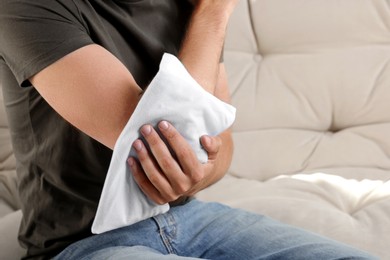 Photo of Man using heating pad on sofa, closeup. Space for text