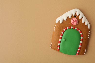 Photo of Christmas house shaped gingerbread cookie on brown background, top view. Space for text