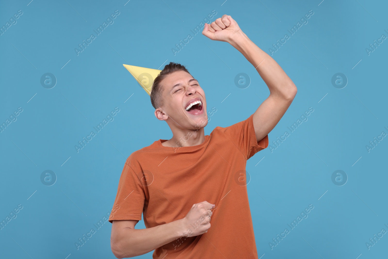 Photo of Happy young man in party hat on light blue background