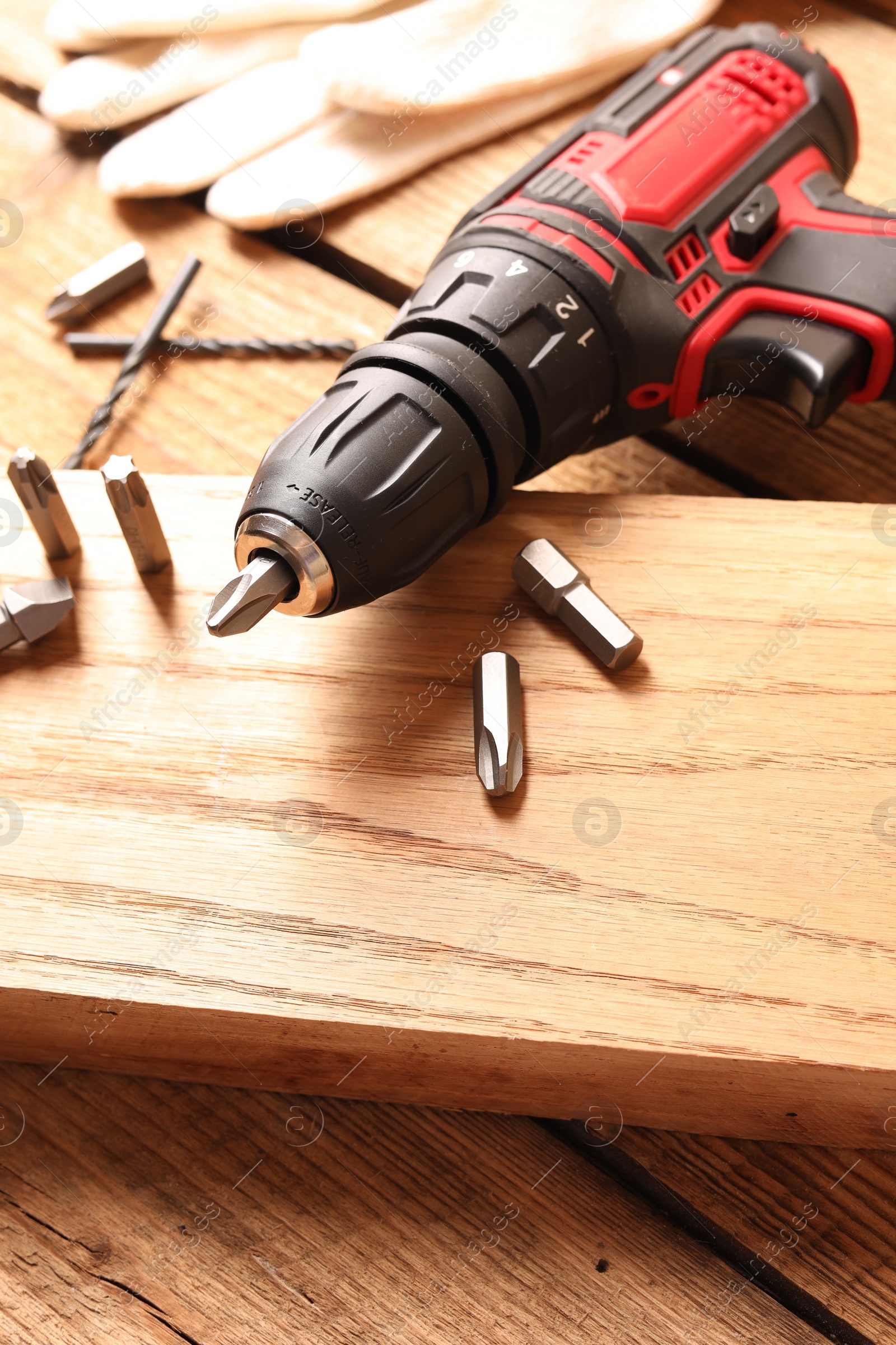 Photo of Electric screwdriver with bit set on wooden table, closeup