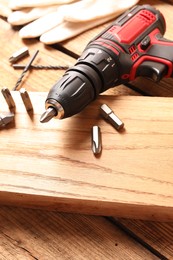 Electric screwdriver with bit set on wooden table, closeup