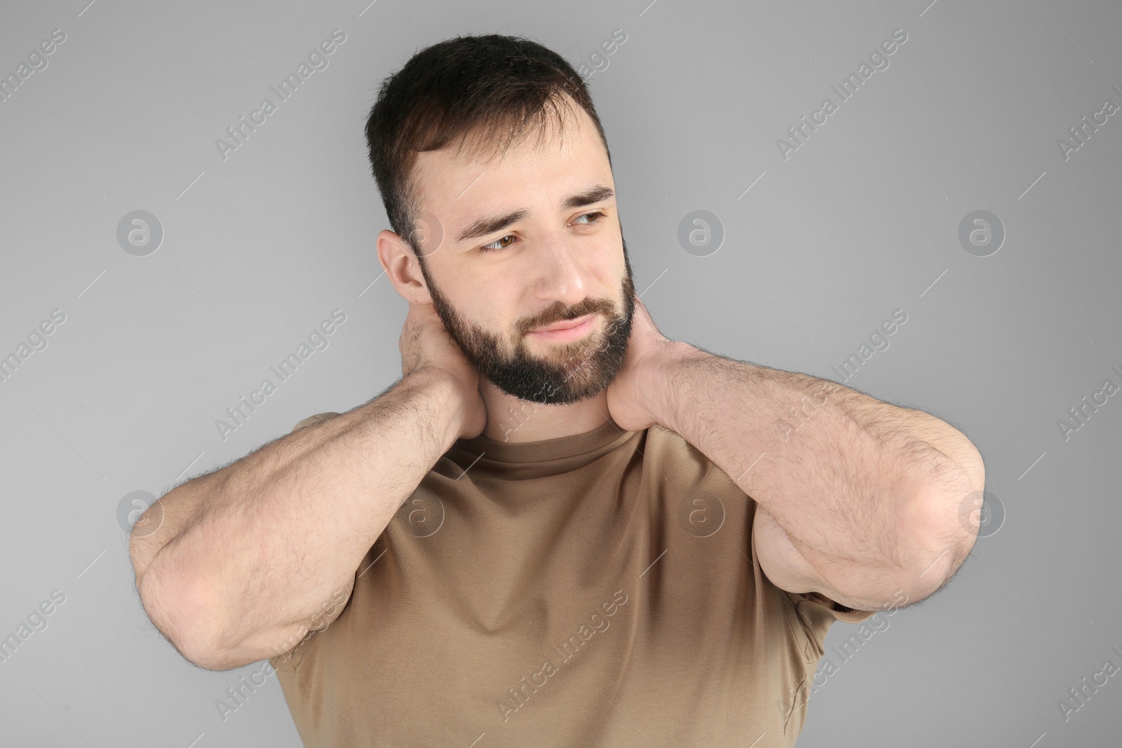 Photo of Young man suffering from neck pain on light background