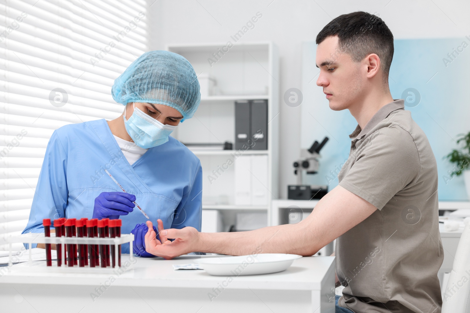 Photo of Laboratory testing. Doctor taking blood sample from patient at white table in hospital