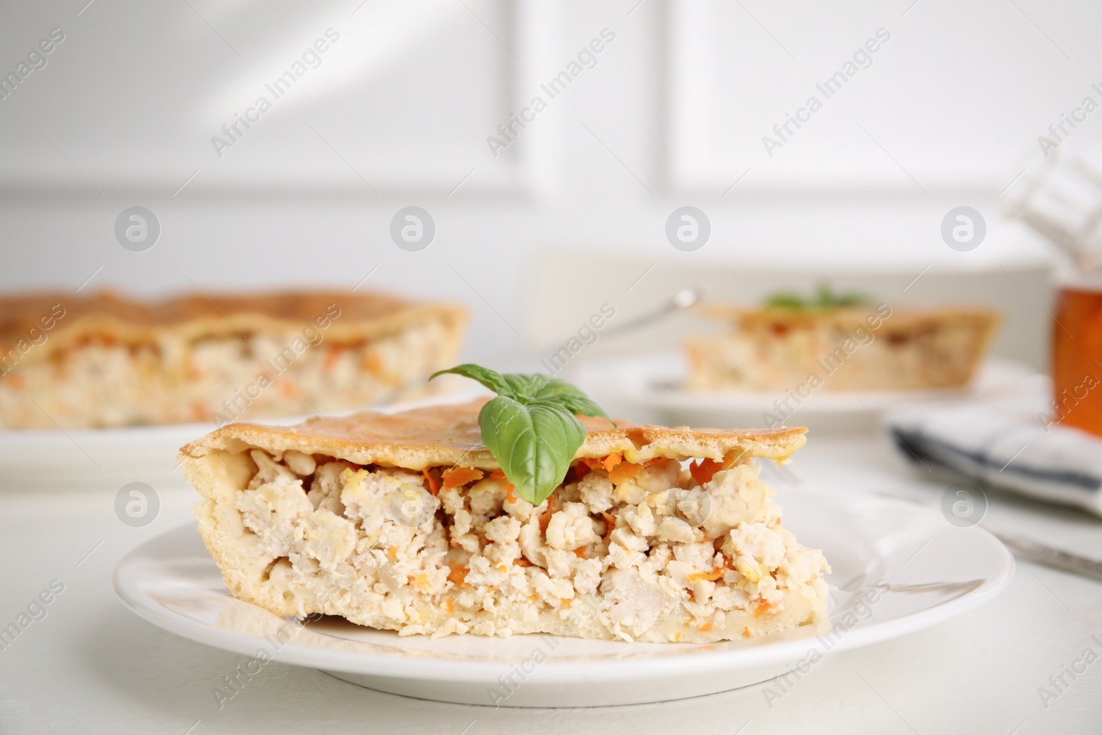 Photo of Piece of delicious pie with meat and basil on white table