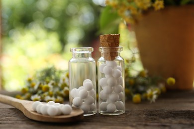 Photo of Bottles of homeopathic remedy and flowers on wooden table