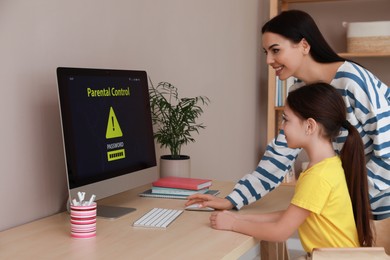 Mom installing parental control on computer at table indoors. Child safety